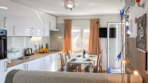 A compact kitchen with a dining area, a sofa, and a view of the outside. - Stunning apartment in Omisalj with WiFi (Omisalj)