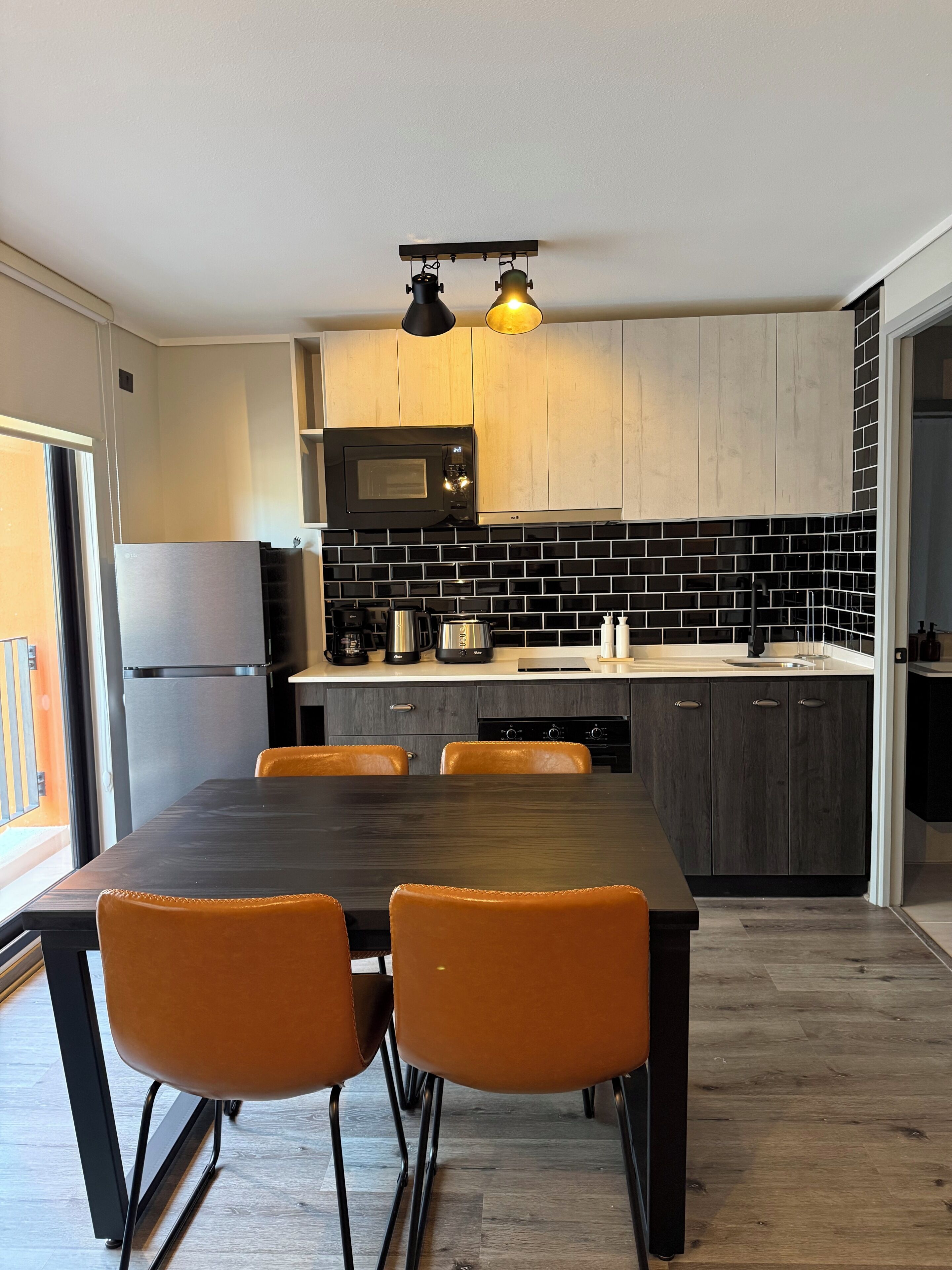 A modern kitchen with a dining table and chairs, a microwave, and a coffee maker.