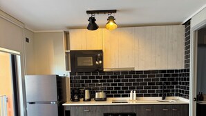 A modern kitchen with a dining table and chairs, a microwave, and a coffee maker. - Valpo Coast Suites · Modern Apartment + Parking + Rooftop (Valparaíso)