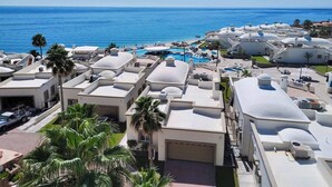 Et resort med flere swimmingpools, palmer og udsigt over havet.