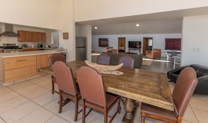 A spacious kitchen with modern appliances, a dining area with a wooden table and leather chairs, and a living area with sofas and a TV. - Ranch Retreat near Santa Fe • Indoor Pool, Hot Tub & Big Skies (Lamy)