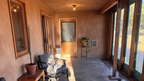 A spacious room with a concrete floor, a wooden door, and large windows.