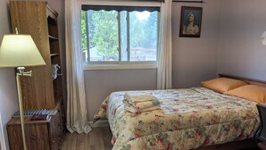 A bedroom with a bed, a nightstand, a lamp, a window with curtains, a wooden wardrobe, and a painting on the wall. - Fun Pool for kids, parents, minutes to Niagara Falls, Clifton Hill, restaurants (Niagara Falls)