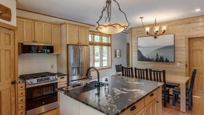 A kitchen with wooden cabinets, a stainless steel refrigerator, a gas stove, and a large island with a sink. - Private Whitefish Chain Family Retreat on Little Pine Lake - Sleeps 10 (Crosslake)