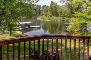 A lakeside deck with a dock, chairs, and tables. - Private Whitefish Chain Family Retreat on Little Pine Lake - Sleeps 10 (Crosslake)