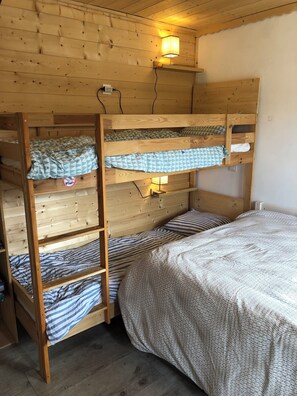 A bunk bed with a headboard, a bedside table with a lamp, and a plain wall. - CHARMING SOUTH-FACING 2-ROOM APARTMENT WITH LARGE TERRACE (Les Gets)
