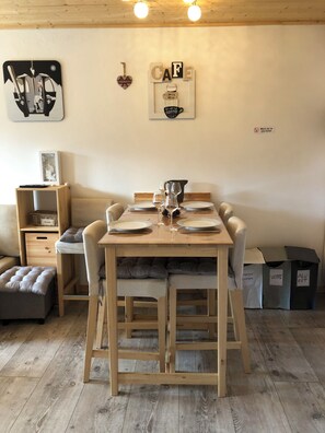 A wooden dining table set for four with plates, glasses, and a pitcher. - CHARMING SOUTH-FACING 2-ROOM APARTMENT WITH LARGE TERRACE (Les Gets)