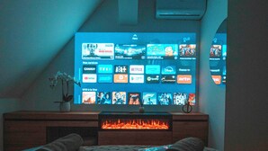 Ein Schlafzimmer mit Fernseher, der verschiedene Streaming-Dienste anzeigt, einem Kamin und einem Bett mit aufgerollten Handtüchern.