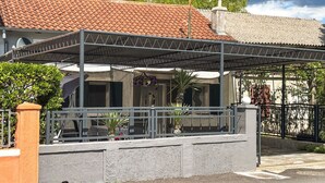 Un espacio al aire libre cubierto, con barandilla de metal, base de concreto y techo de tejas.