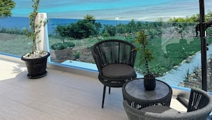 A balcony with a view of the sea, a table, two wicker chairs, and a potted plant. - Beachfront villa in Samaná with private pool (Las Galeras)