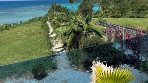 A tropical landscape with a clear view of the ocean, lush greenery, and a well-maintained lawn. - Beachfront villa in Samaná with private pool (Las Galeras)