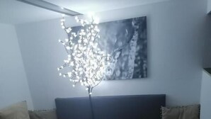 A modern living room with a sofa, a small side table, and a wall-mounted light fixture. - Le Domaine d'Eva (Libramont-Chevigny)