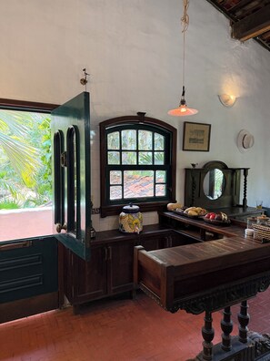A room with a large window, a wooden bench, a table with fruits, and a decorative vase. - Hacienda Palma Escondida (Brisas de Zicatela)