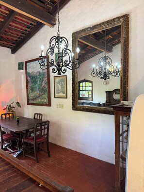 A dining area with a wooden table, chairs, two chandeliers, and a large mirror on the wall. - Hacienda Palma Escondida (Brisas de Zicatela)
