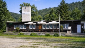 A building with a sign reading 'BREZOVY HÁJ' and a row of tables with umbrellas. - Cozy group stay · 4 rooms · Shared facilities · Outdoor pool (Březová)