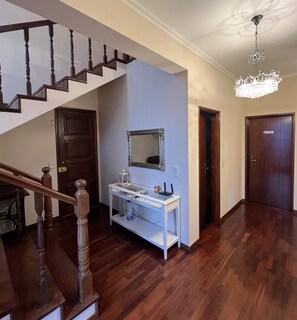 A hallway with a wooden staircase, a white console table with a mirror, and a chandelier. - House with sea and airport views (Santa Cruz)