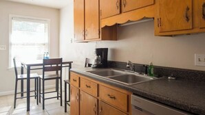 Una cocina con armarios de madera, encimera de granito, cafetera y un lavabo.
