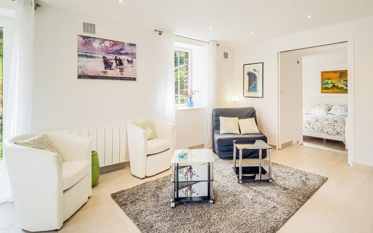 Ein modernes Wohnzimmer mit einem weißen Sofa, einem schwarzen Sofa, einem Couchtisch und einem Bett mit floralem Überwurf.