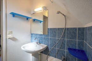 Un baño con un lavabo blanco, azulejos azules, un espejo y una ducha.