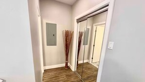 Un pasillo con suelo de madera, un espejo y una puerta.