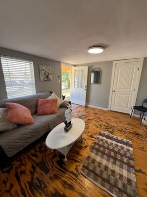A living room with a sofa, coffee table, rug, and a door leading outside. - Perfect for 2: Pet Friendly (San Angelo)