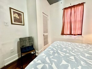 A bedroom with a bed, a chair, a door, and a window with curtains. - Sleeps 4/ Fenced Yard/ Pet Friendly/ Near Downtown (San Angelo)