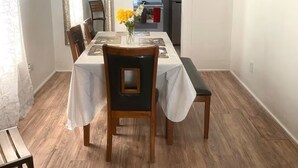 A dining area with a table, chairs, a ceiling fan, a mirror, and a kitchen in the background. - Sleeps 4/ Fenced Yard/ Pet Friendly/ Near Downtown (San Angelo)