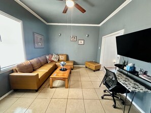 A living room with a sofa, coffee table, ottoman, and a desk with a chair. - Sleeps 4/ Fenced Yard/ Pet Friendly/ Near Downtown (San Angelo)