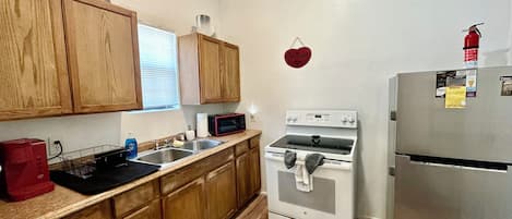 A kitchen with wooden cabinets, a stainless steel refrigerator, a microwave, and an oven.
