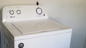 A white Amana washer and dryer unit with control knobs for water level and wash temperature. - Sleeps 4/ Fenced Yard/ Pet Friendly/ Near Downtown (San Angelo)