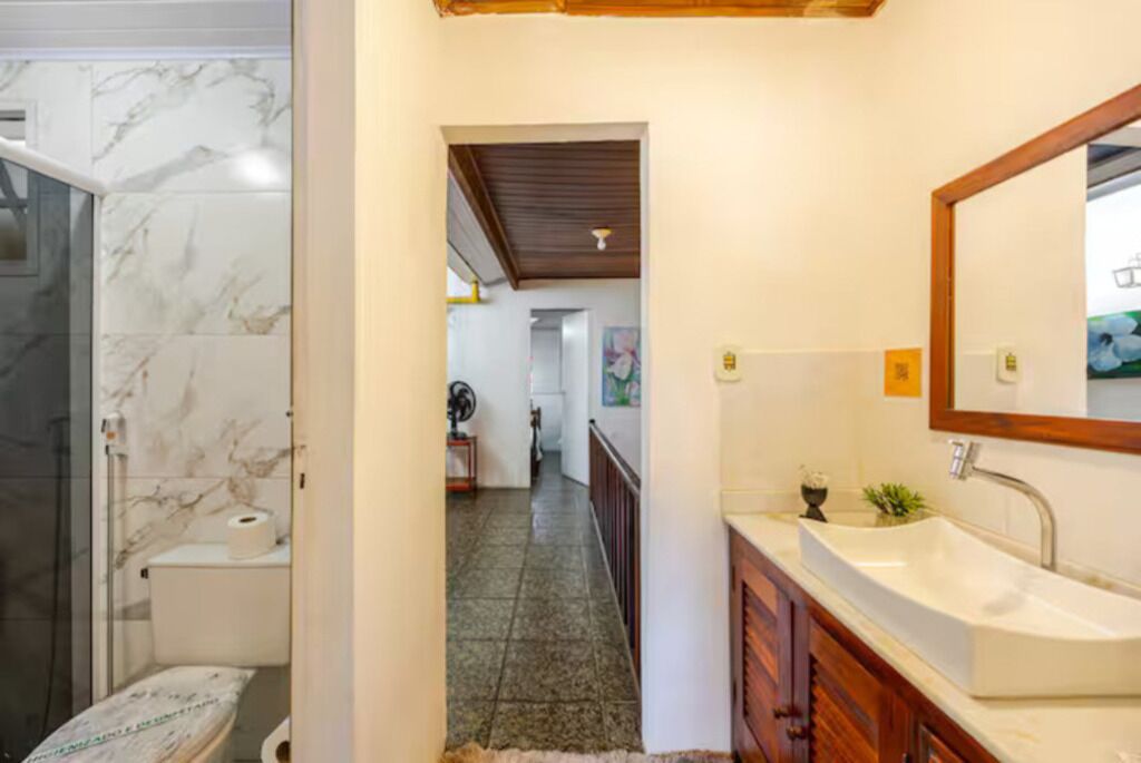 Un bagno con doccia in marmo, un water e un lavandino con specchio.