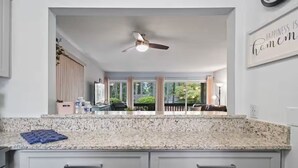 A kitchen with a granite countertop, white cabinets, a ceiling fan, and a view of the outdoors. - Birdie Bungalow - Sleeps 8 - Prime Location (Pinehurst)