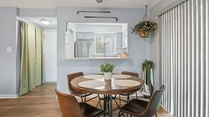 A dining area with a round table, chairs, ceiling fan, and a view of the kitchen. - Birdie Bungalow - Sleeps 8 - Prime Location (Pinehurst)