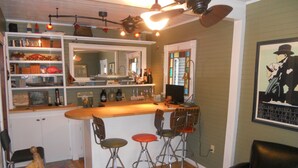 A bar area with stools, a counter, and shelves with various items.