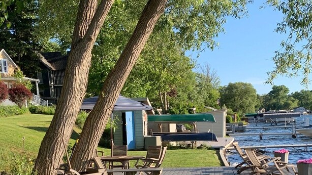 A wooden deck with Adirondack chairs, a small table, and a blue door.