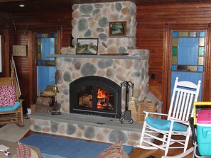 A stone fireplace with a fire, a wooden mantel, and a framed picture above it.