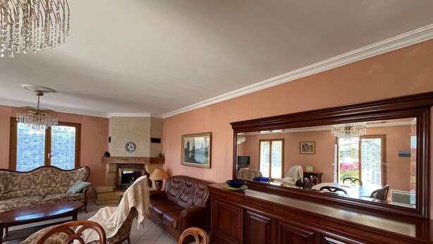 Uma sala de estar com lareira, sofá, mesa de jantar e um espelho grande.