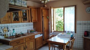 Uma cozinha com armários de madeira, geladeira, pia e mesa de jantar com cadeiras.