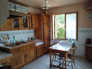 Eine Küche mit Holzschränken, einem Kühlschrank, einer Spüle und einem Esstisch mit Stühlen.