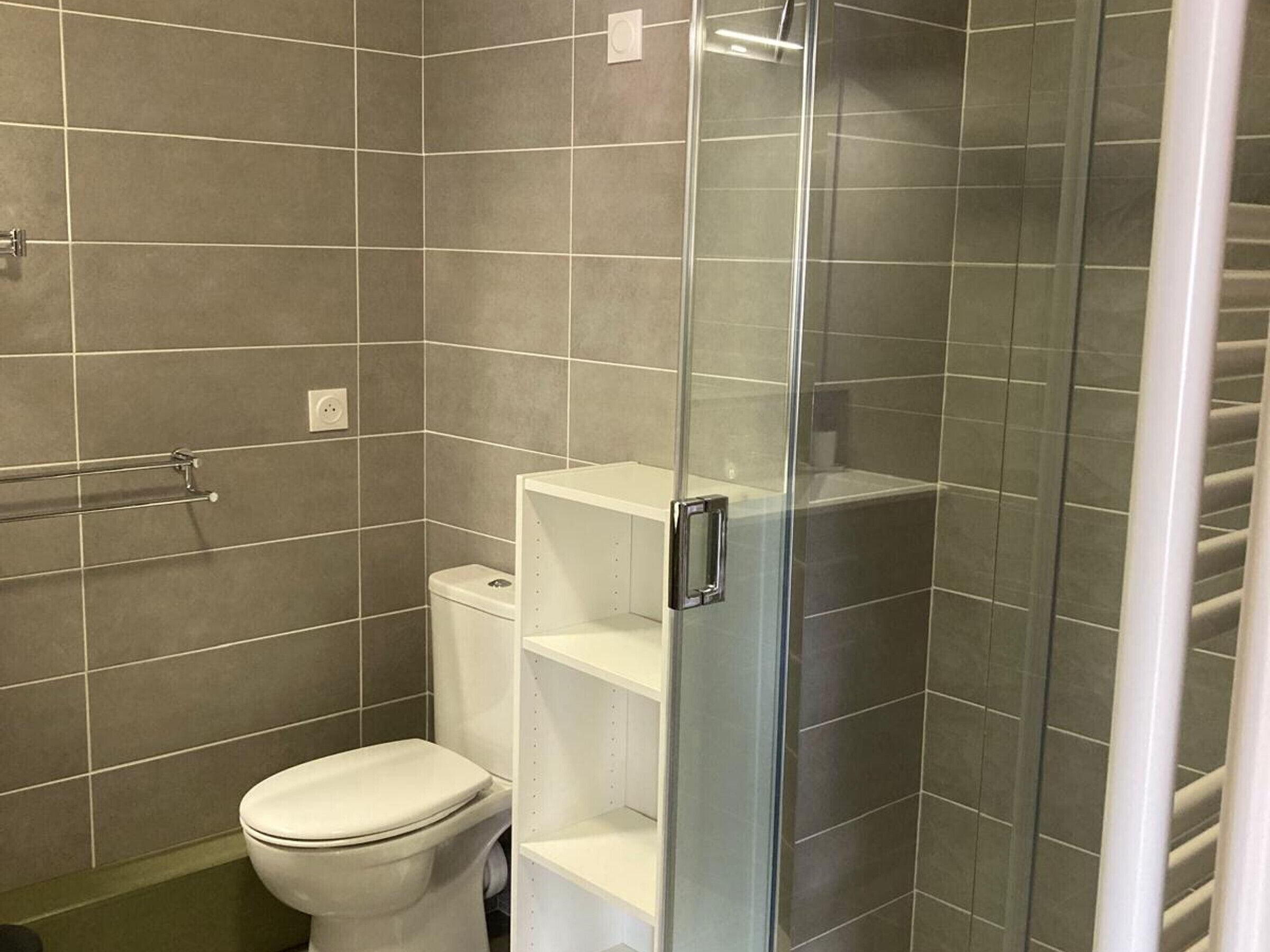 A bathroom with a toilet, a shower enclosure, and a glass door.