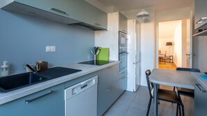 Une cuisine moderne équipée d’un lave-vaisselle, d’un évier et d’un coin repas avec une table et des chaises.