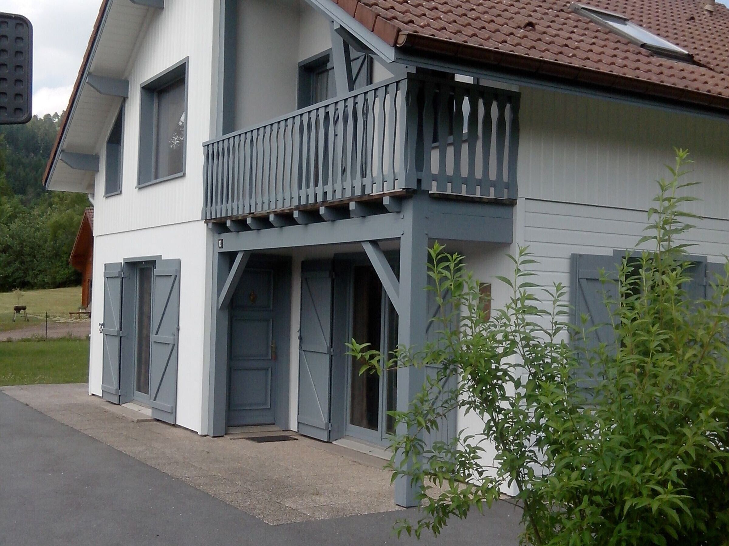 Een gebouw met twee verdiepingen, een balkon en een garage.