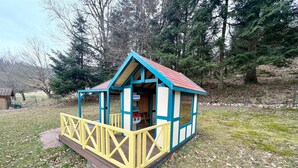 A small, single-story wooden structure with a red roof and blue trim, featuring a yellow railing and a door labeled "NOKIA". - Spacious chalet near Gérardmer (Gerbamont)