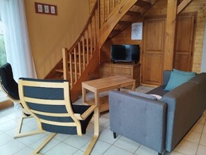 A wooden interior with a staircase, a television, a sofa, and a chair. - Spacious chalet near Gérardmer (Gerbamont)