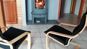 A room with a wood-burning stove, two wooden chairs, and a tiled floor. - Spacious chalet near Gérardmer (Gerbamont)