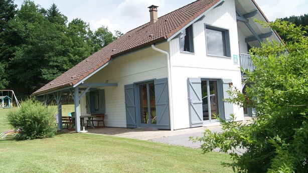 A two-story house with a covered porch, a patio, and a swing set in the yard. - Spacious chalet near Gérardmer (Gerbamont)
