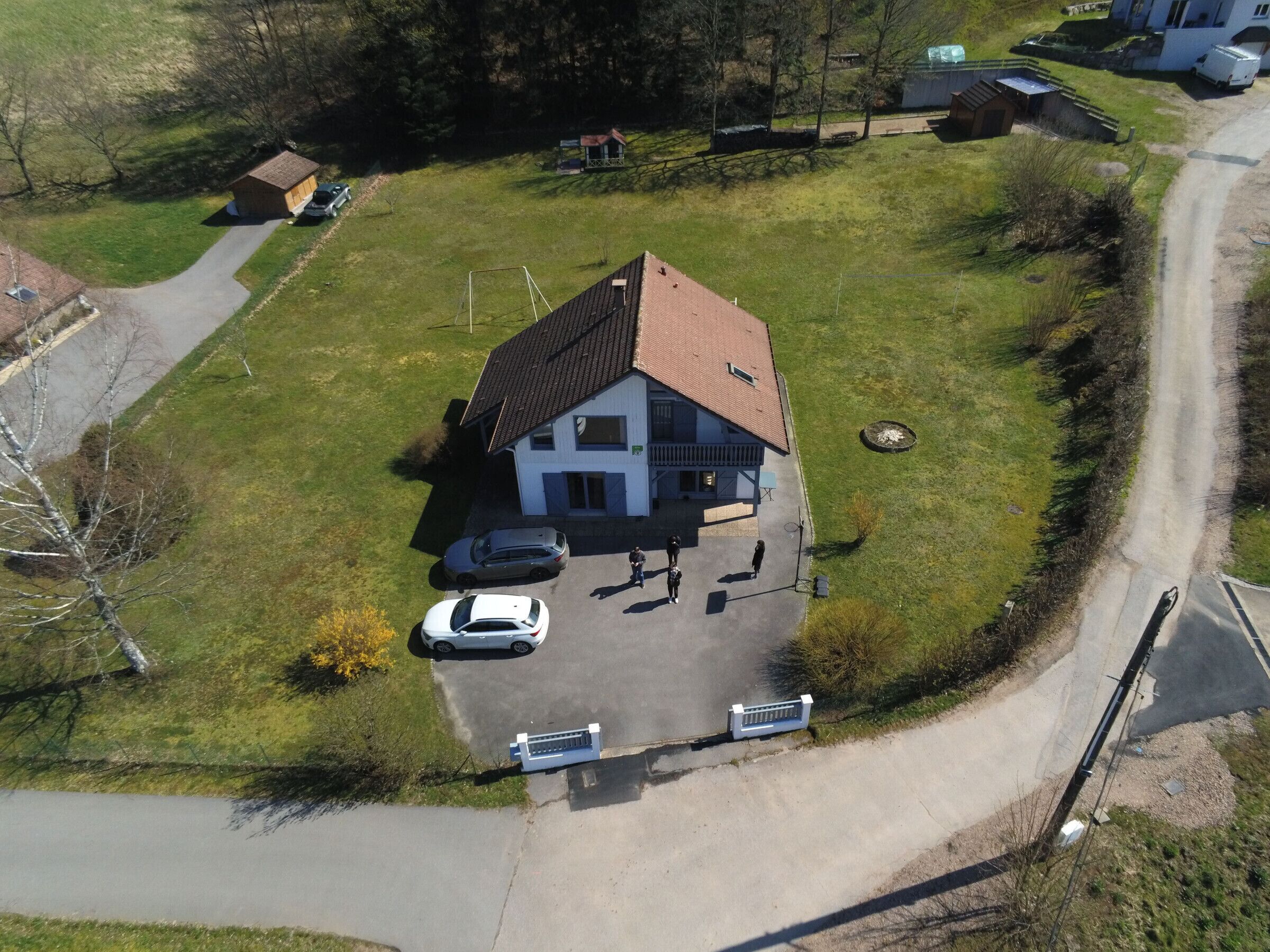 Eine Luftaufnahme eines Hauses mit schrägem Dach, einer Auffahrt und einem kleinen Parkplatz.
