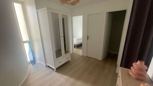 A room with a bed, wardrobe, and a small table with decorative items. - 2-Room Apartment in La Grande-Motte, Near Beach and Shops, Private Parking (La Grande-Motte)