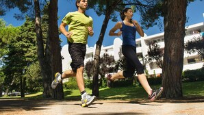 Two people jogging on a path surrounded by trees and a building in the background. - 2-Room Apartment in La Grande-Motte, Near Beach and Shops, Private Parking (La Grande-Motte)
