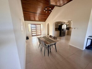 A spacious dining area with a high ceiling and wooden beams, leading to a kitchen with modern appliances. - Barbados Bliss at Platinum Palace | Poolside 3-Bed | Oistins (Oistins)